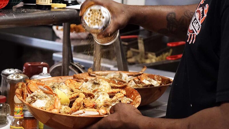 Staff pouring spices on crabs in a bowl